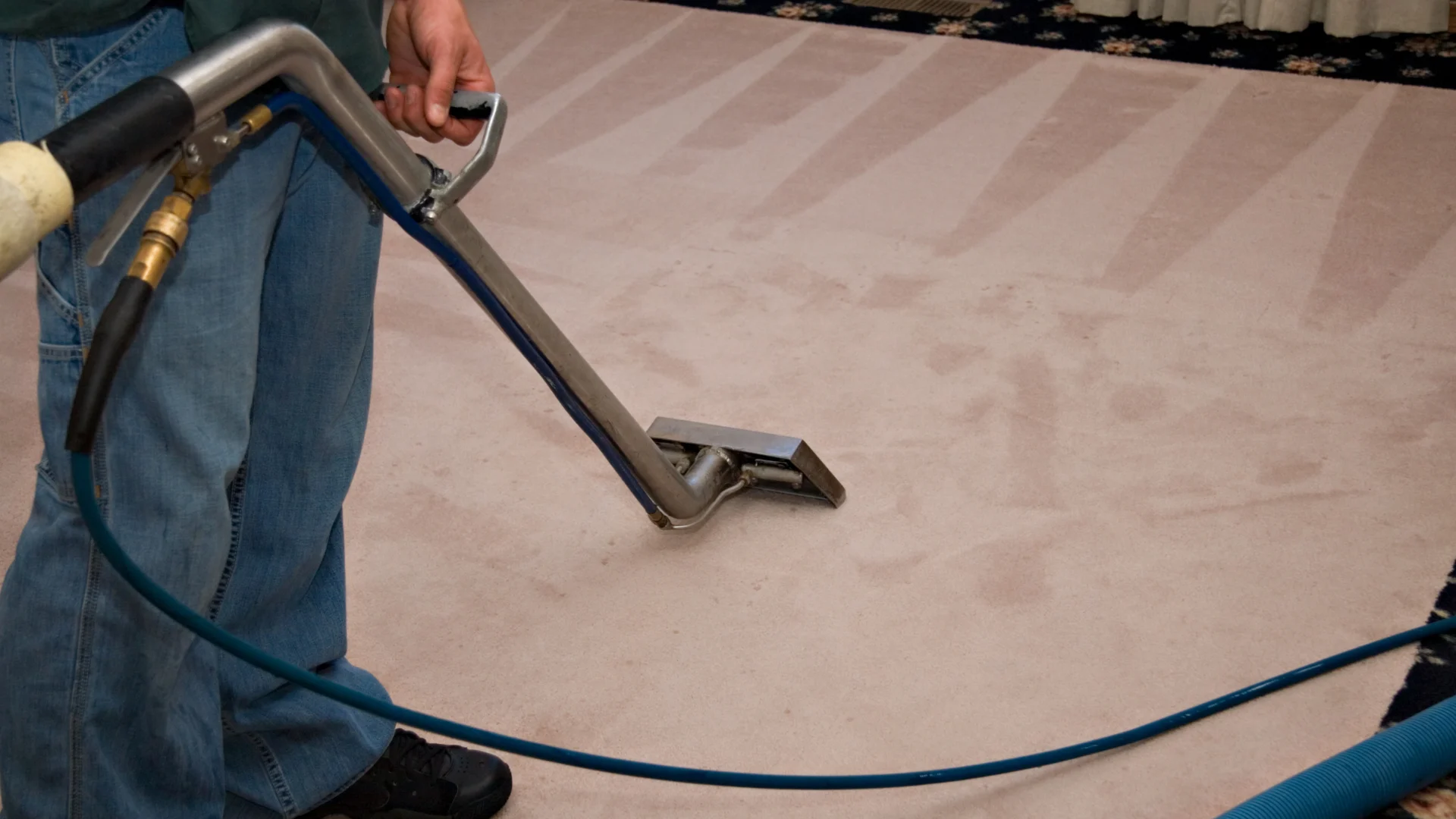 Professional carpet cleaning service using vacuum machine to clean living room carpet.